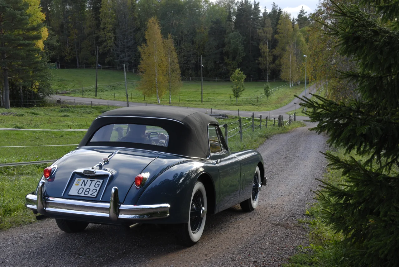 XK150 snett bakifrån på en grusväg med suffletten uppfälld