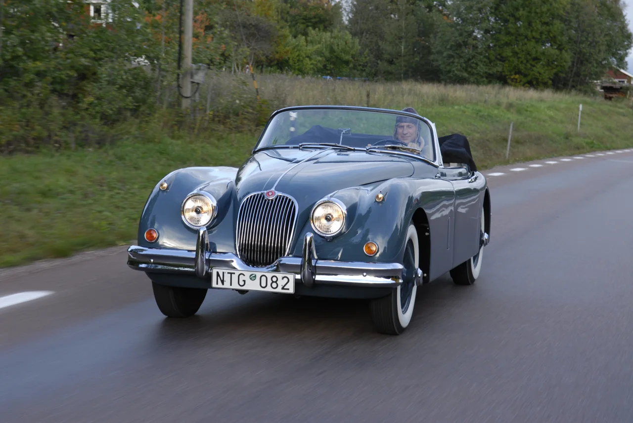 Jaguar XK150 med nedfälld sufflett på en landsväg