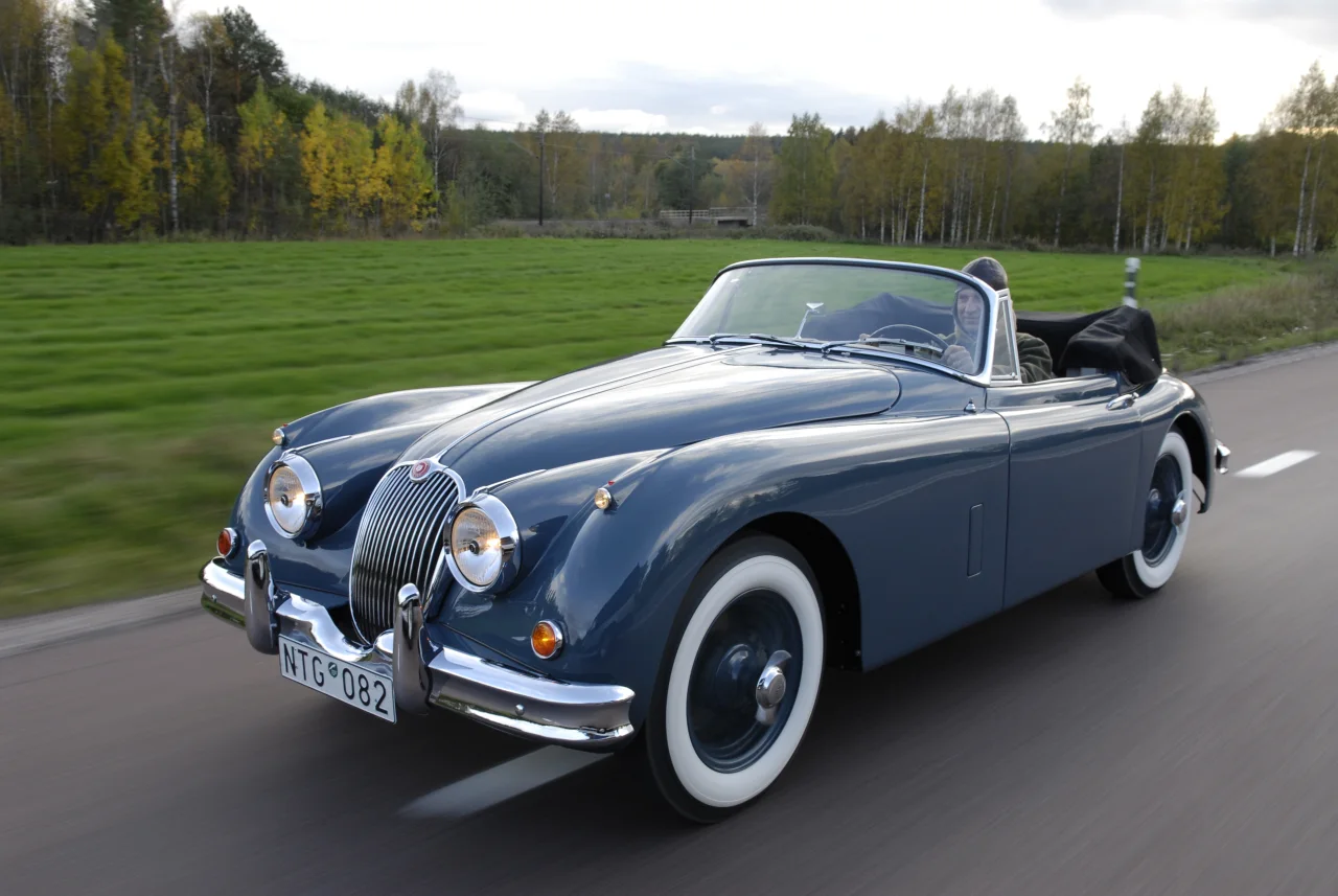 XK150 på vägen vid öppna fält med nedfälld sufflett